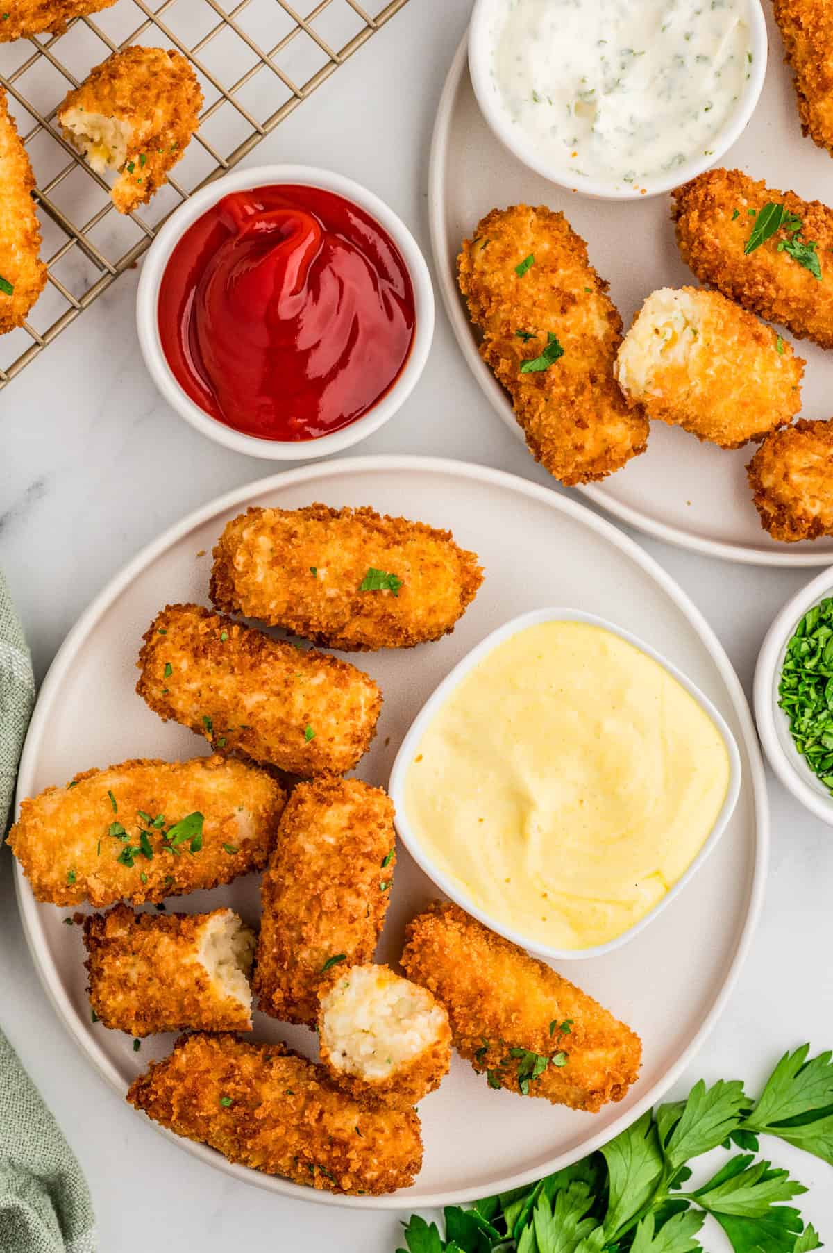 Overhead of Potato Croquettes on plates with parsley and dipping sauces.