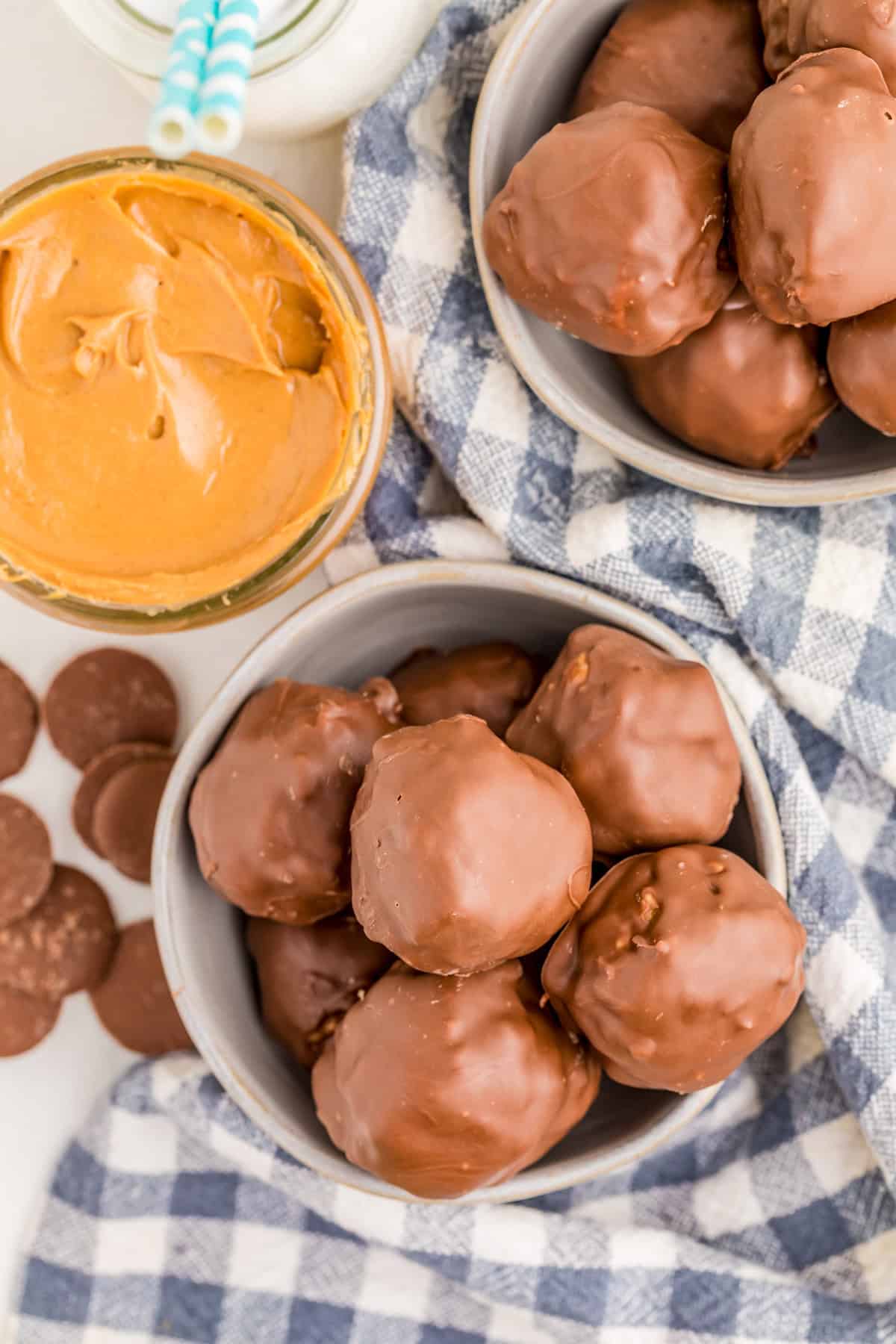 Overhead of peanut butter balls with checkered linen and peanut butter.