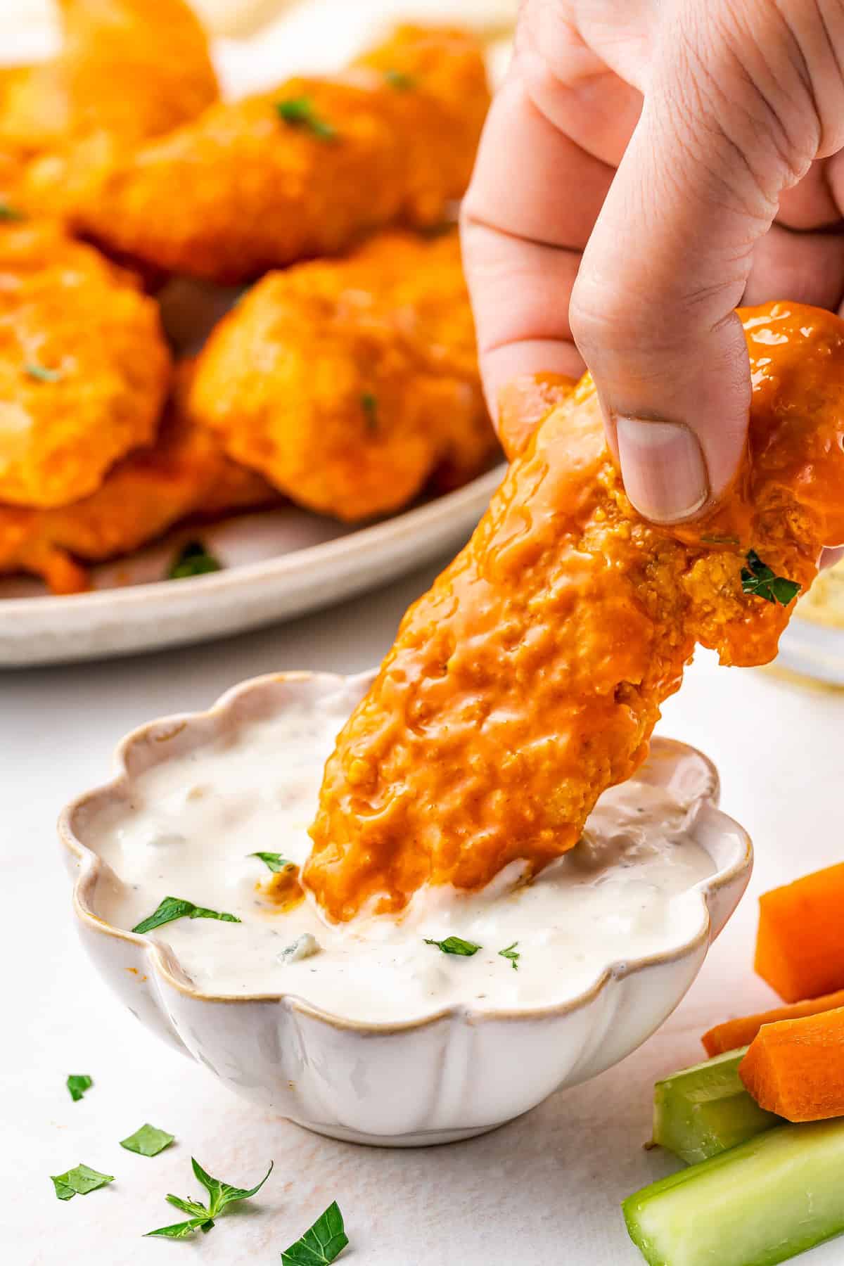 Hand dipping one of the chicken strips in the dipping sauce.