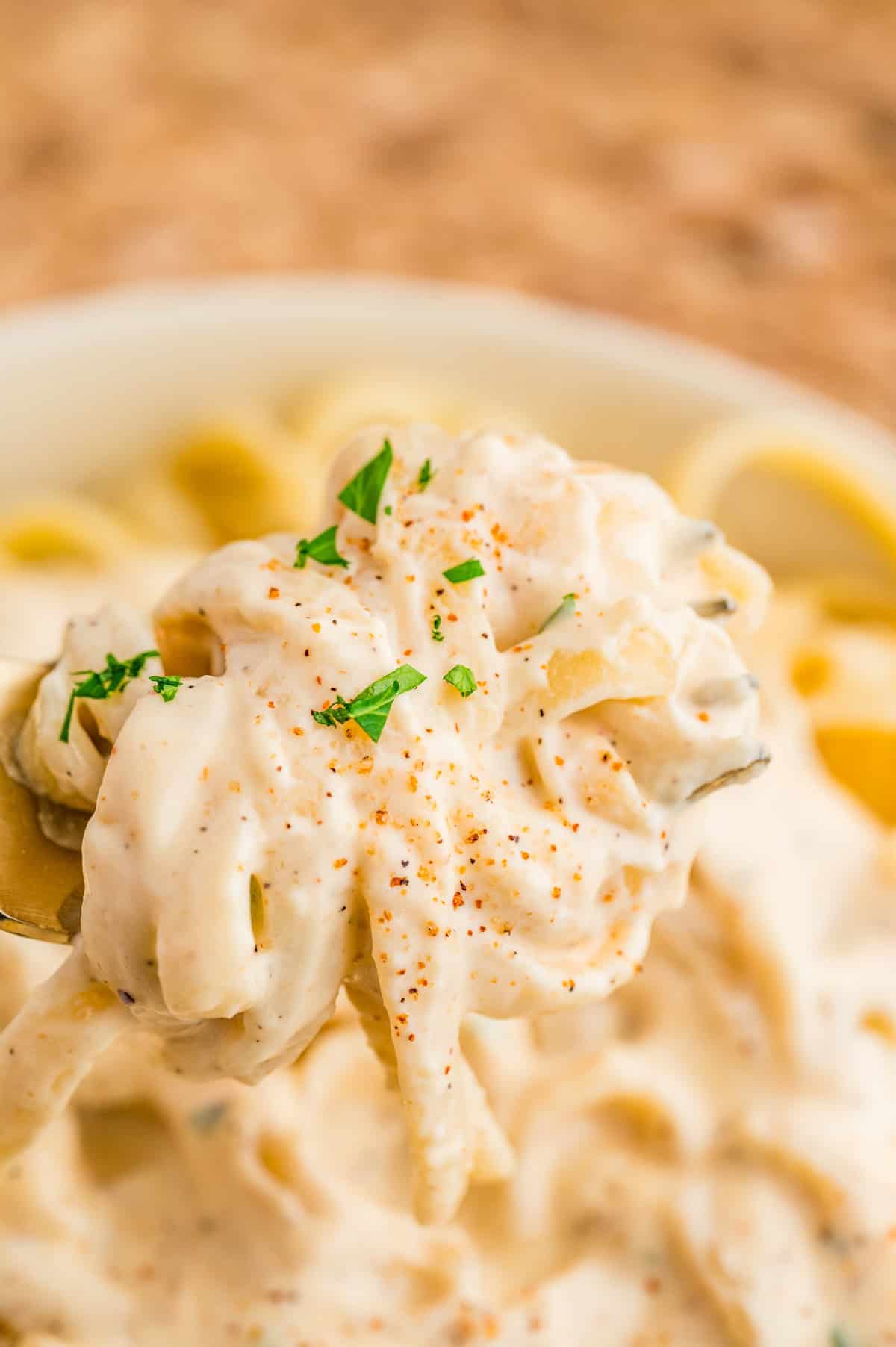 Cajun Alfredo Sauce over pasta close up being held up by fork out of bowl.