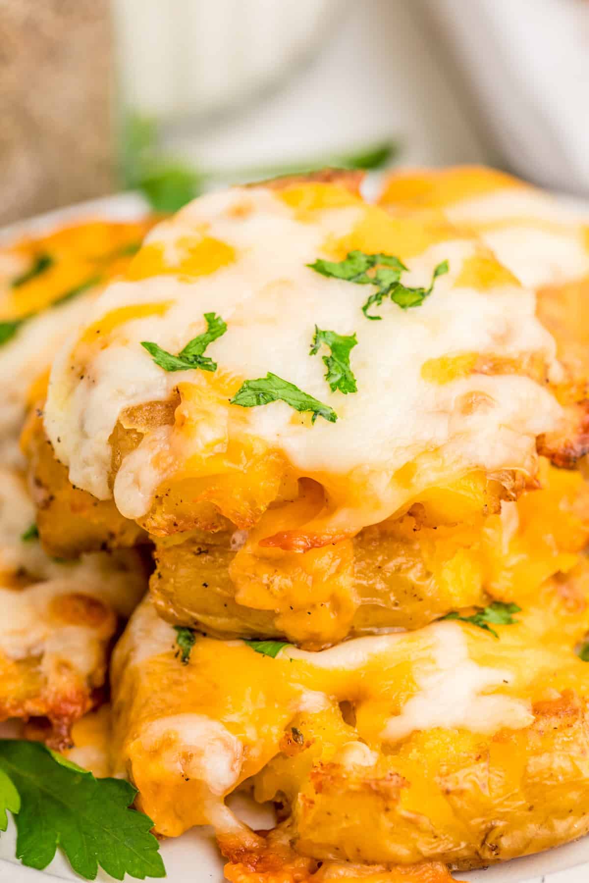 Close up of potatoes stacked showing the melted cheese and parsley.