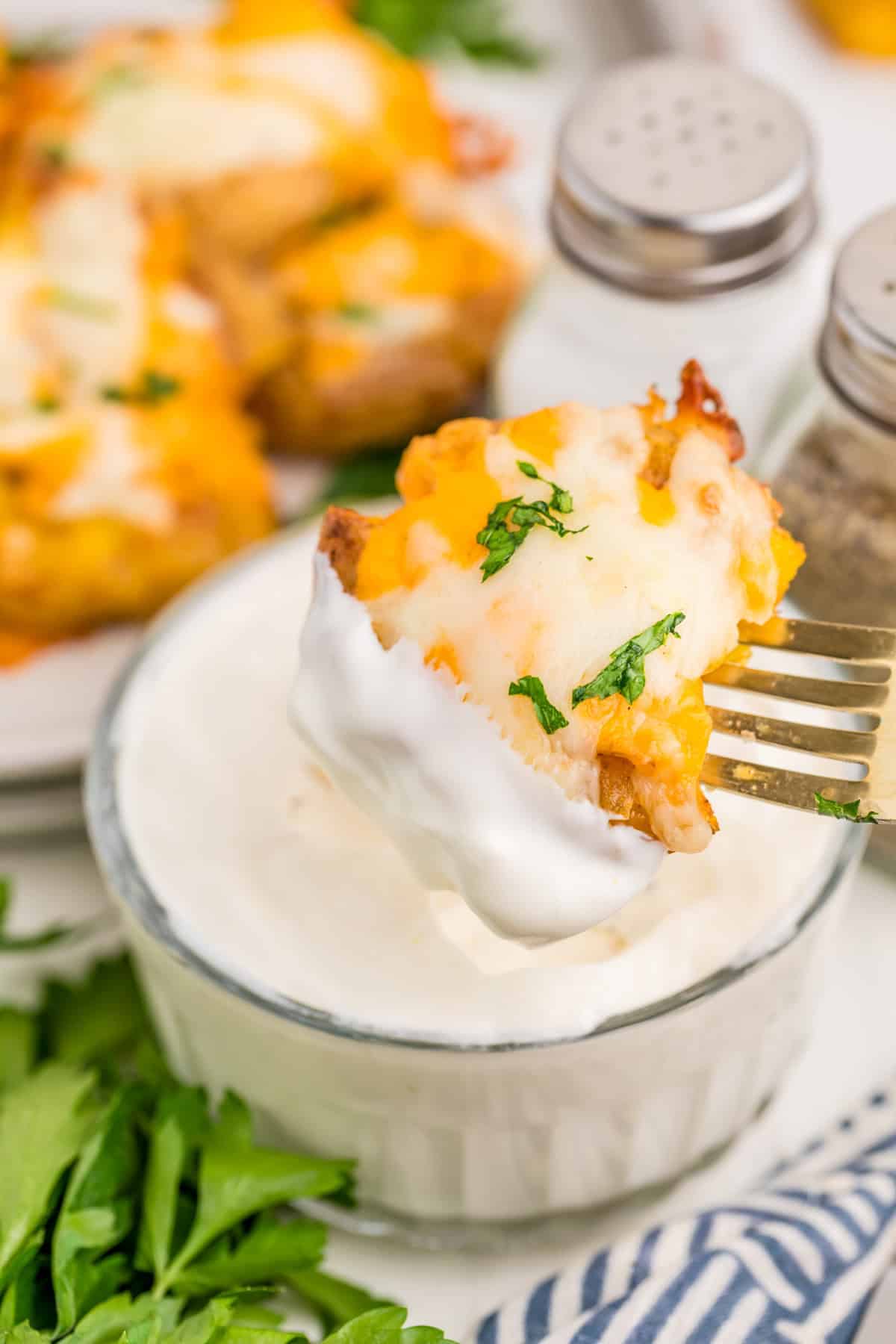 Fork dipping one of the potatoes into sour cream.