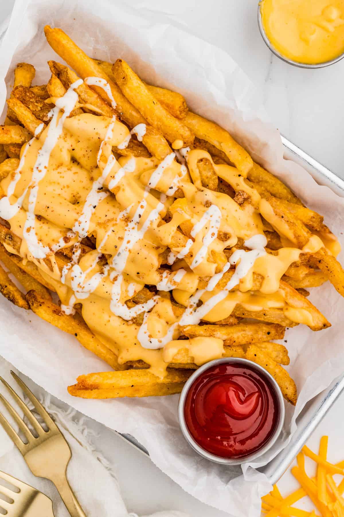 Overhead of finished fries topped with cheese sauce and ranch.