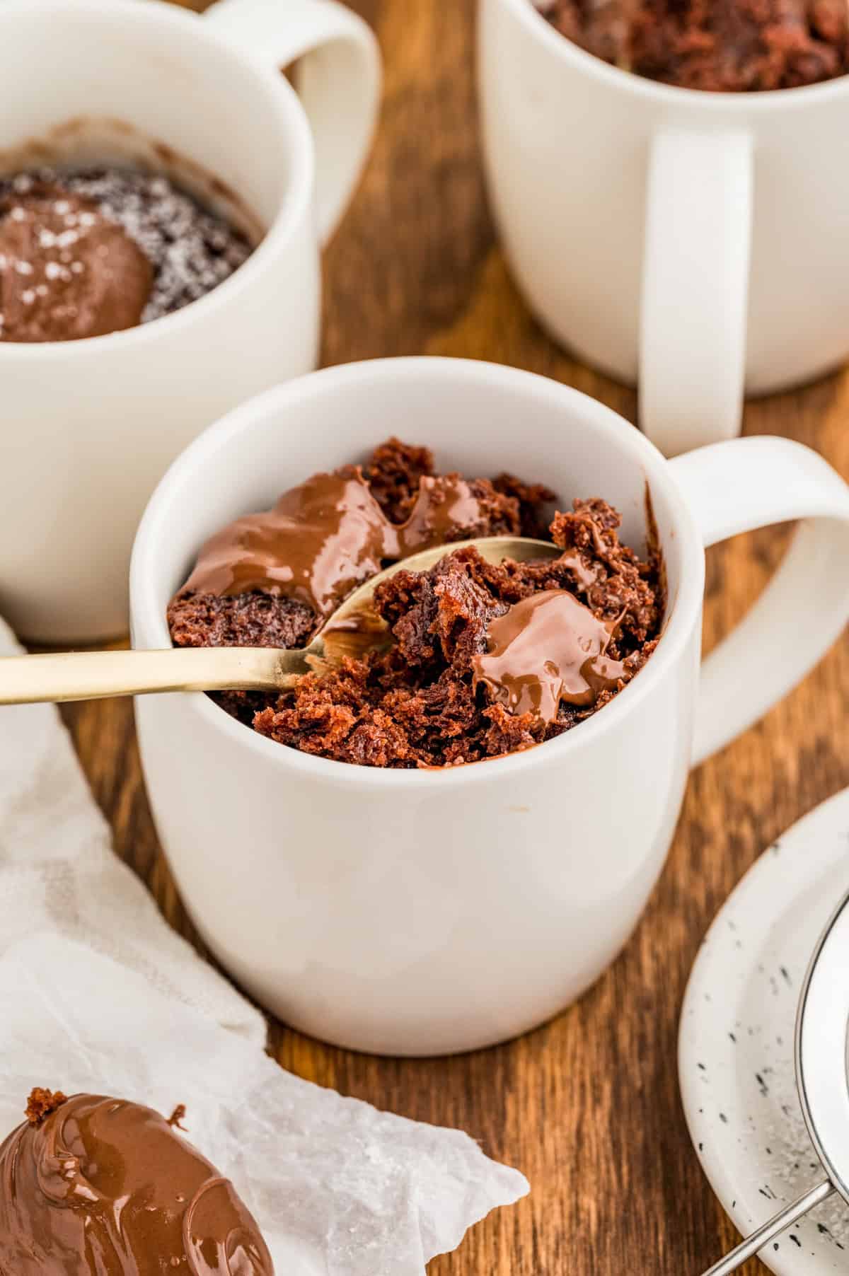 Nutella Mug Cake in white mug with a gold spoon scooping out some of the cake.