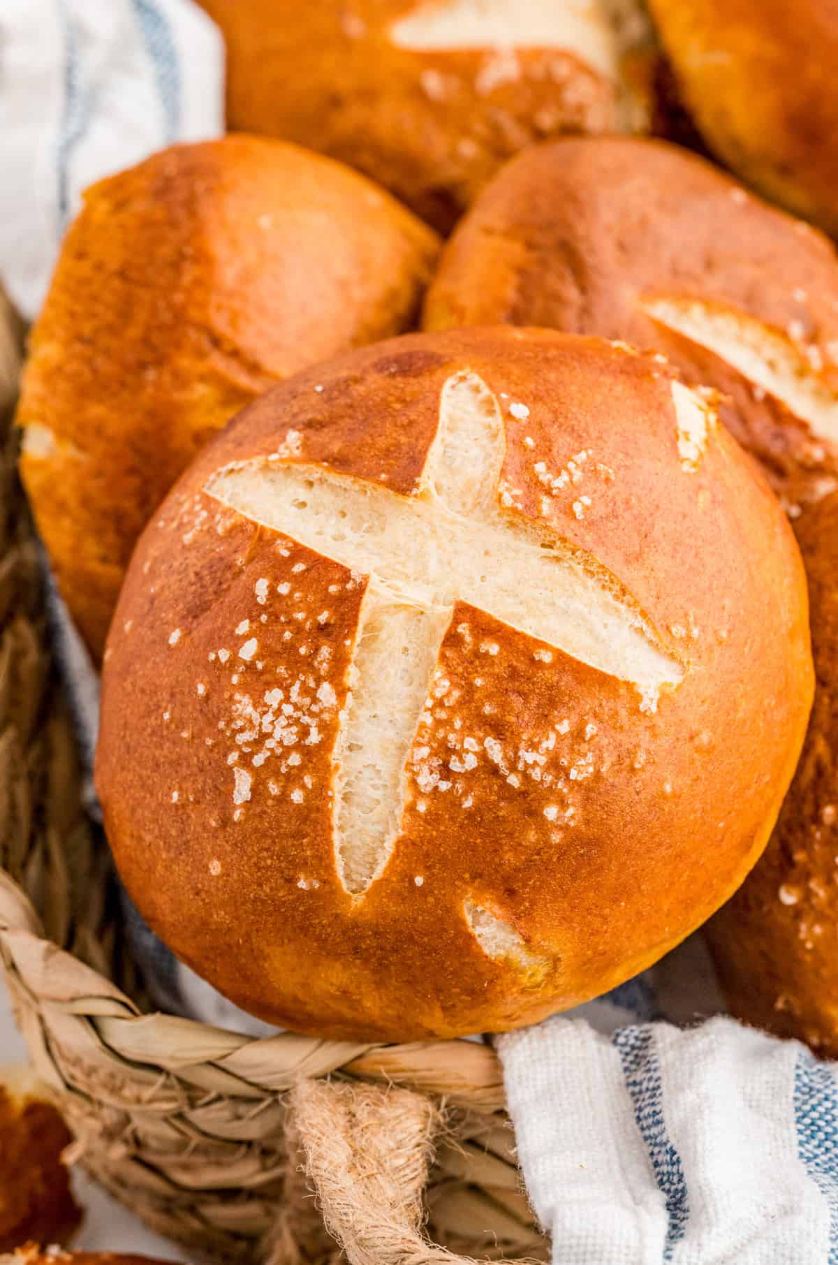 Pretzel Rolls in bread basket showing the cut in top with salt.