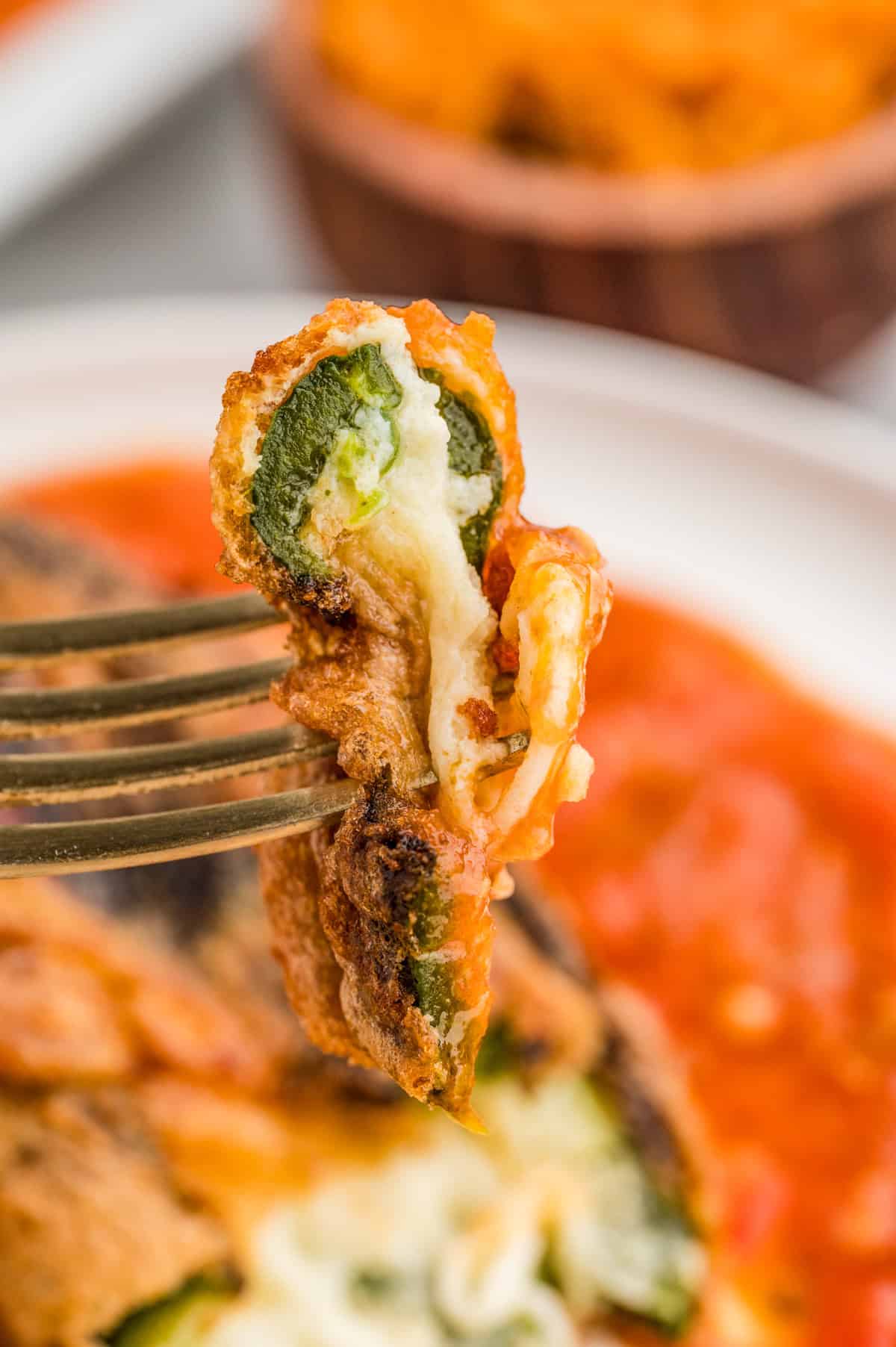 Fork holding up a bite of the Chile Rellenos showing the cheese inside.