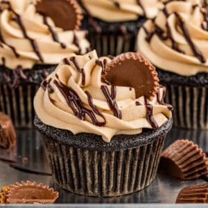 Close up square image of one cupcake frosted with ganache and mini Reese's.