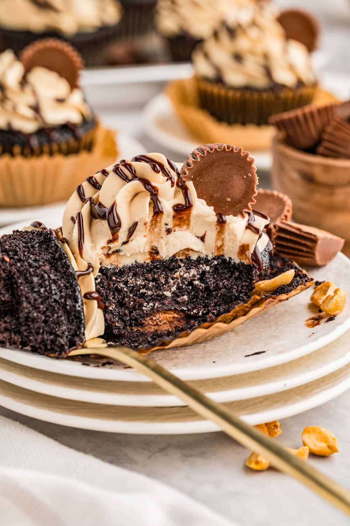 One cupcake on stacked white plates cut in half showing the Reese's in the center.