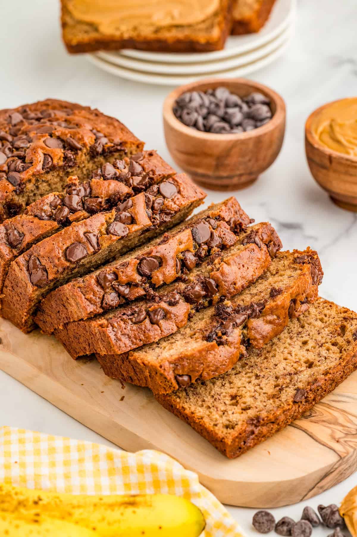 Peanut Butter Banana Bread on wooden board cut in slices topped with chocolate chips.