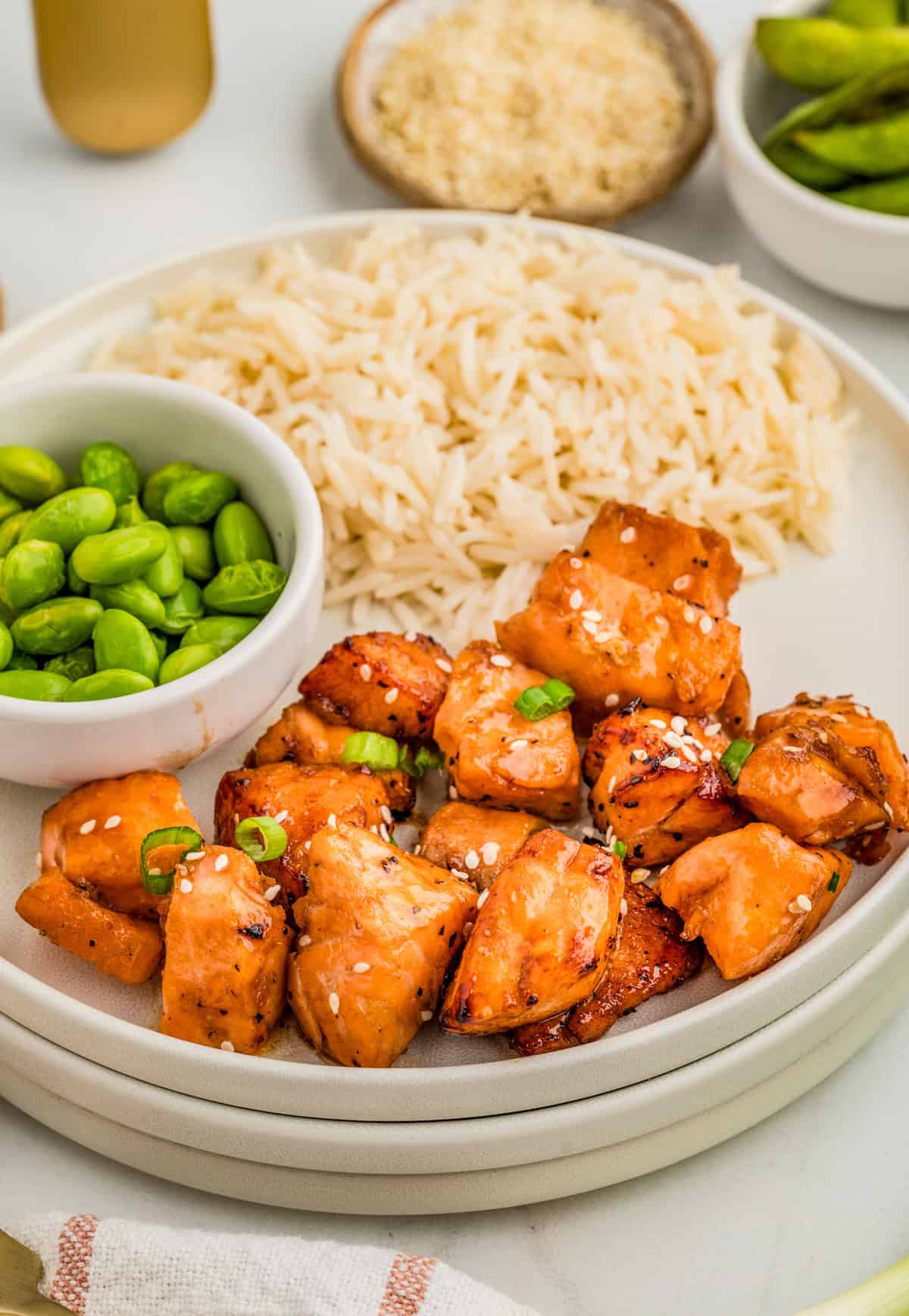 Finished Air Fryer Salmon Bites on stacked plates with rice and edamame.