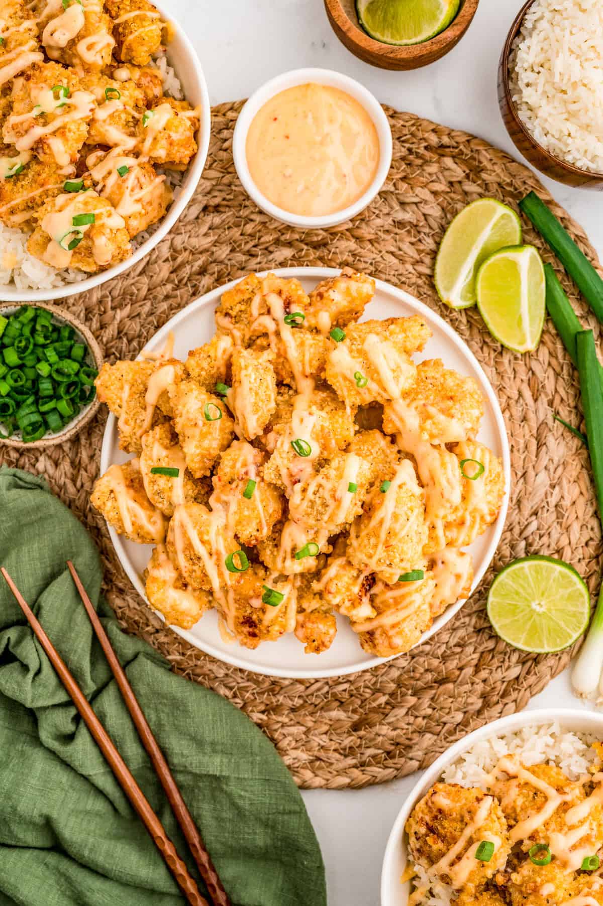 Overhead of finished chicken on plates and bowls with sauce and limes on the side.