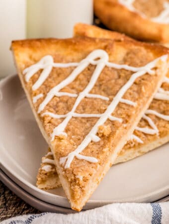 Close up square image of two stacked slices of pizza on white plate with glaze.