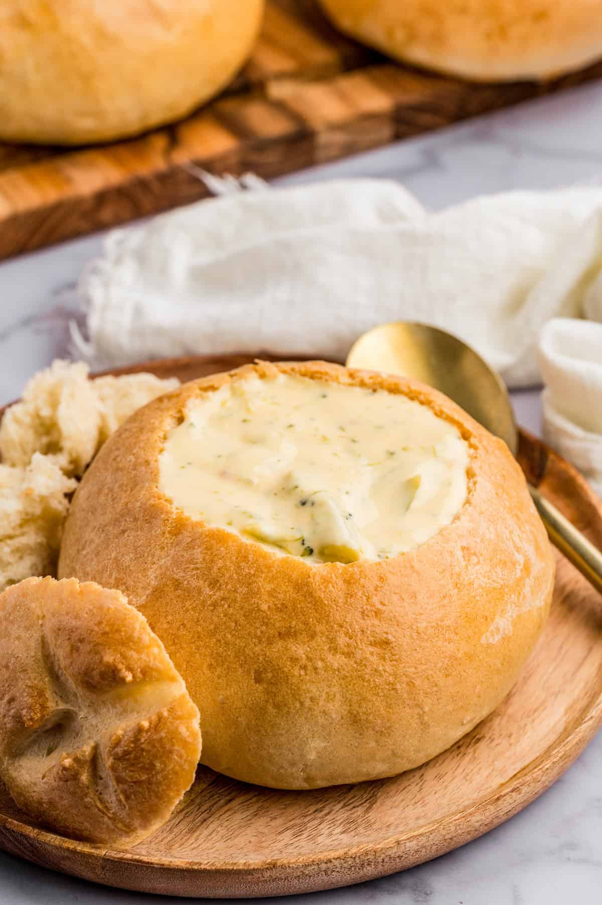 Bread Bowl on wooden plate filled with soup.