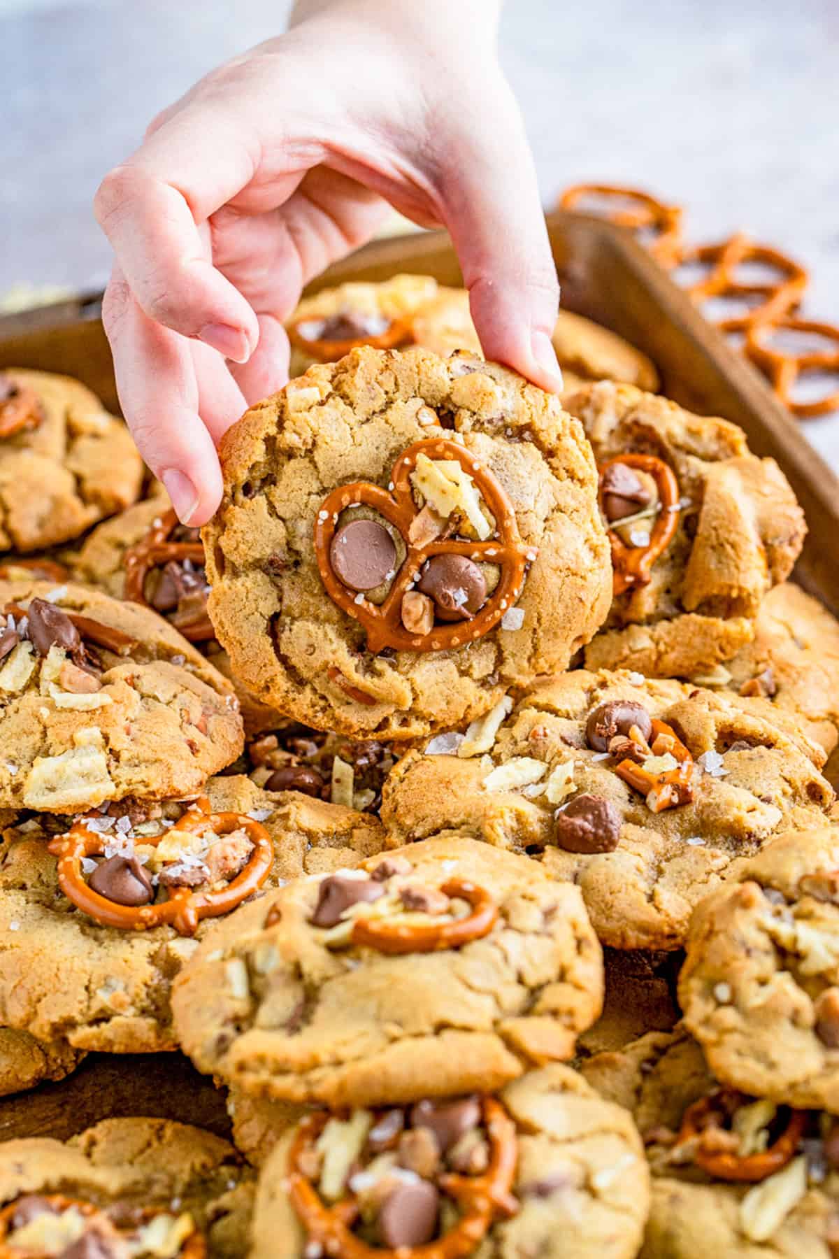 Cookies on baking tray with hand propping one up showing the toppings.