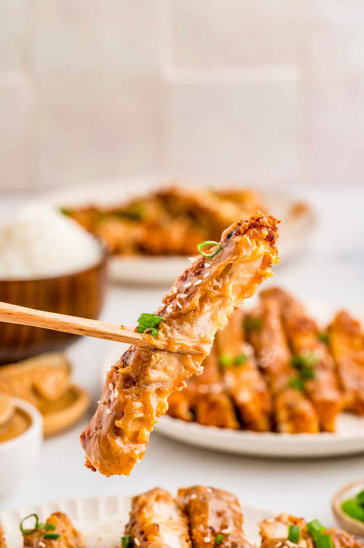 Chopstick holding up one slice of chicken.