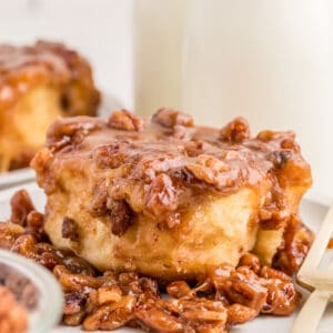 Square image of a finished bun on a plate on top of the pecan mixture.