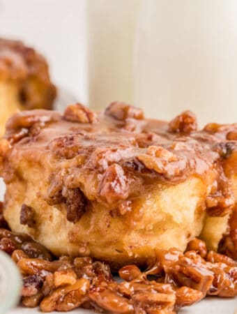 Square image of a finished bun on a plate on top of the pecan mixture.