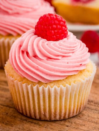 Close up square image of finished cupcake garnished on a round wooden board.