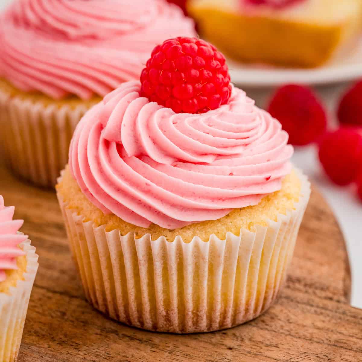 Close up square image of finished cupcake garnished on a round wooden board.