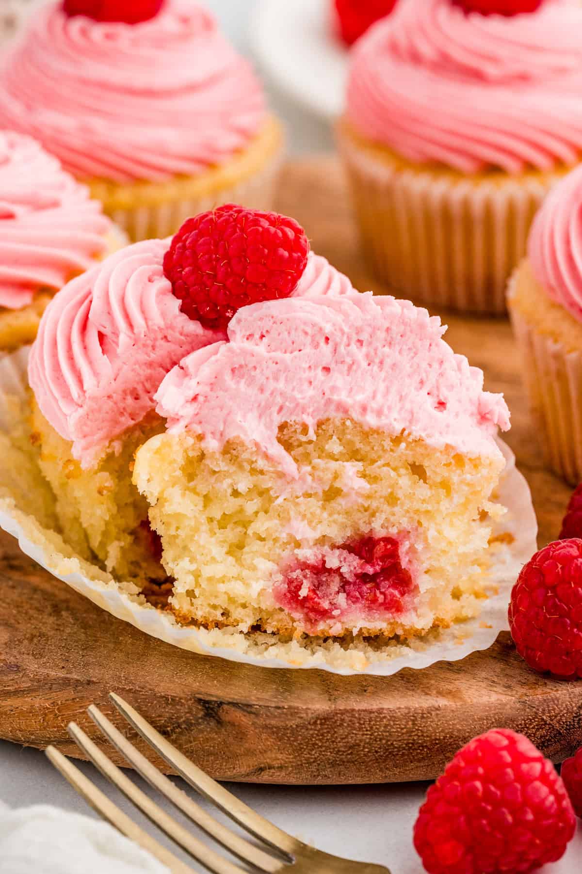 One of the Raspberry Cupcakes cut in half showing the raspberry in the center.
