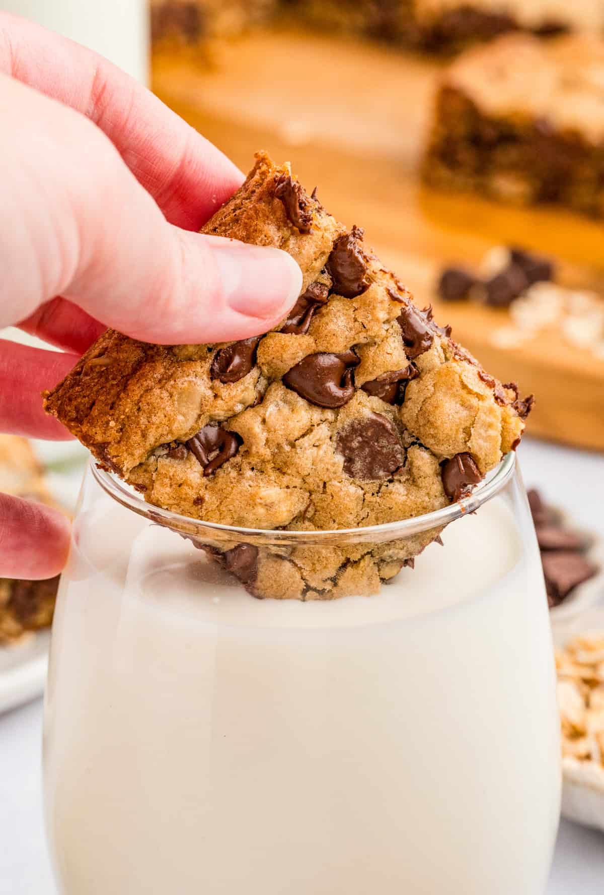 Hand dipping one of the bars into a glass of milk.