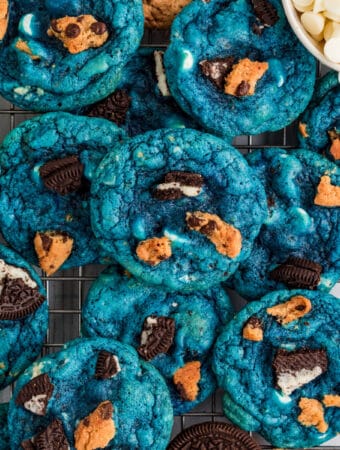 Square image of cookies stacked on top of one another on wire rack.