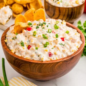 Close up square image of dip in wooden bowl with chips in dip.