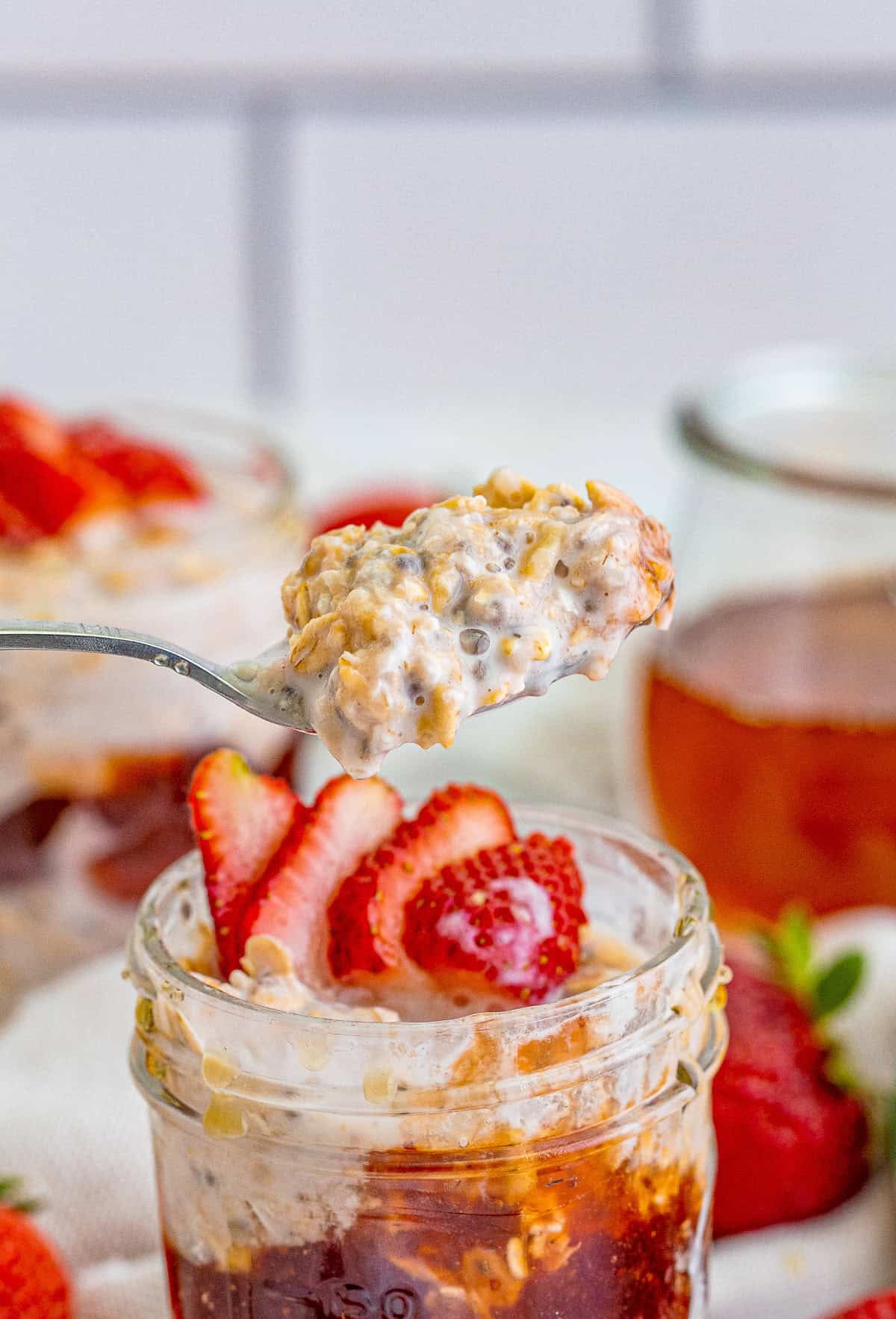 Spoon holding up some of the Strawberry Overnight Oats out of the jar.