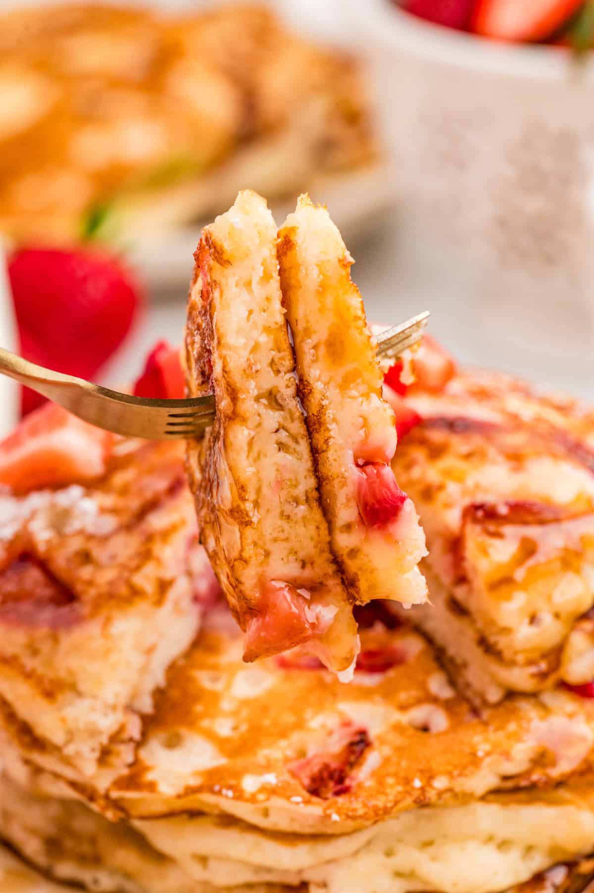 Fork holding up slices of the pancake taken out of the stack.