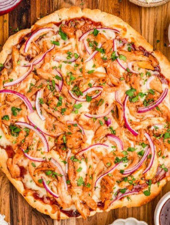 Close up overhead photo of finished pizza uncut on wooden board.