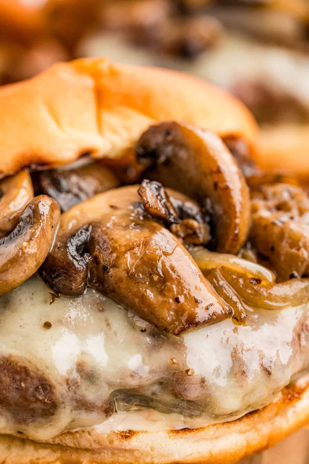 Close up of mushrooms on burger on top of melted cheese.