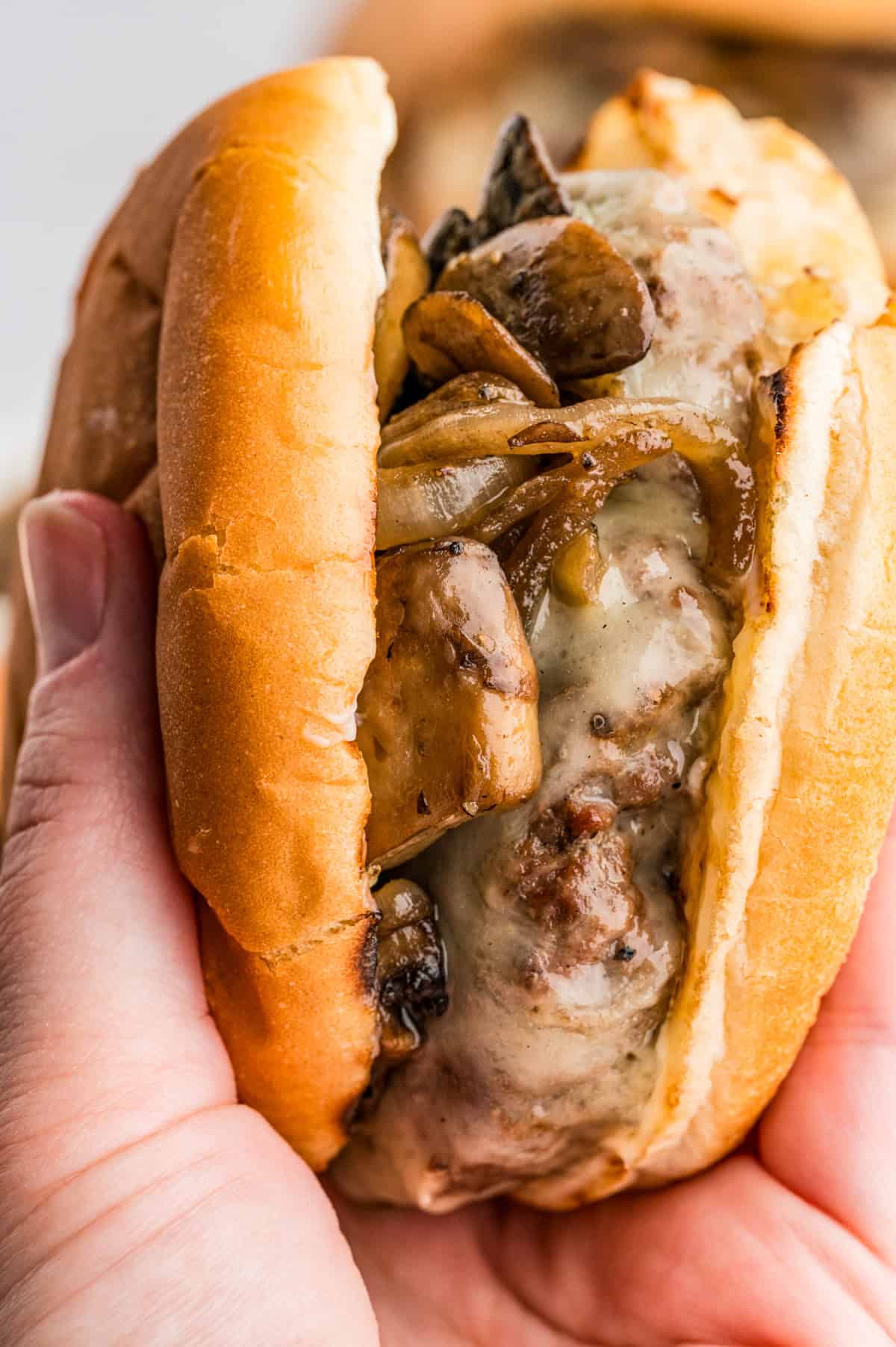 Hand holding up a Mushroom and Swiss Burger showing the layers.