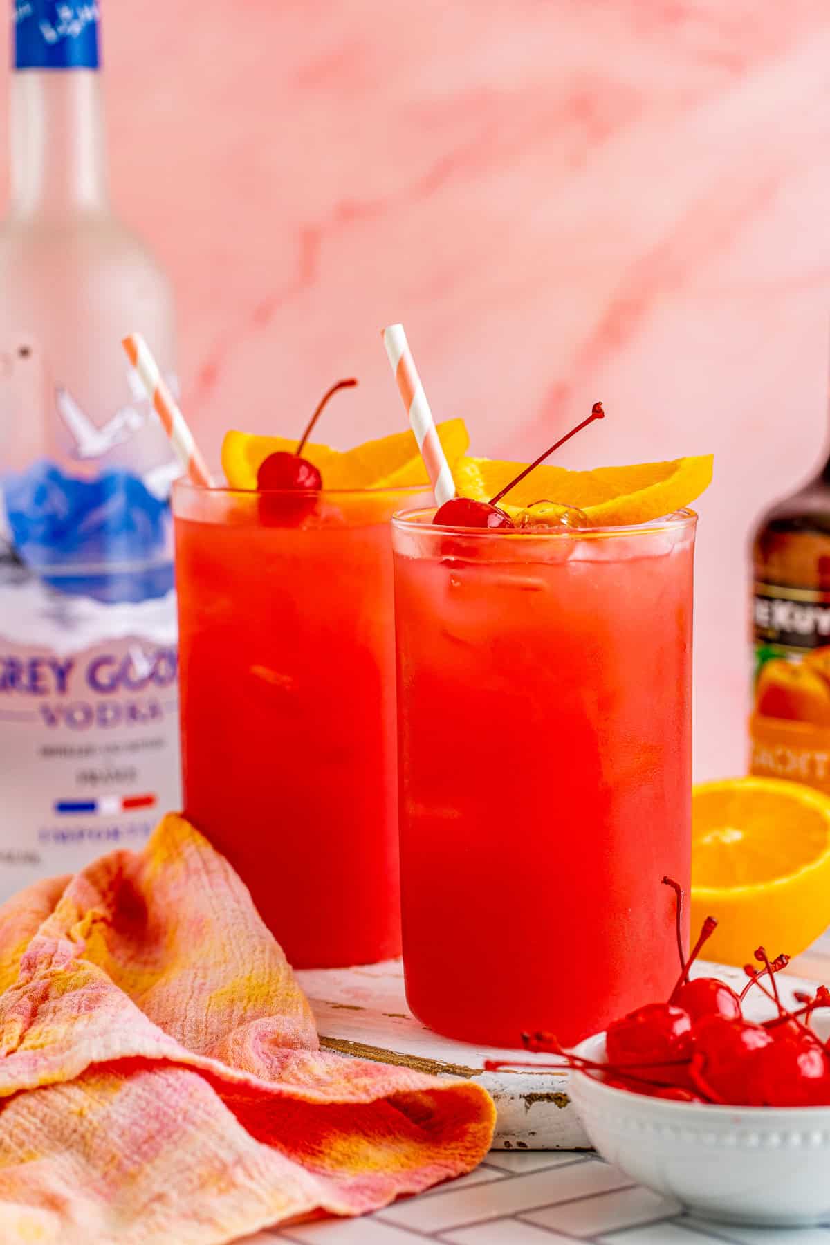 Finished Sex on the Beach Cocktail Recipe garnished with alcohol bottles in background.