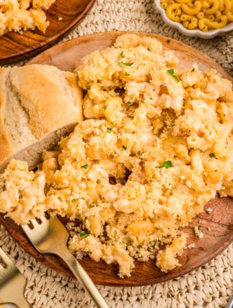 Close up square image of mac and cheese on plate with bread.