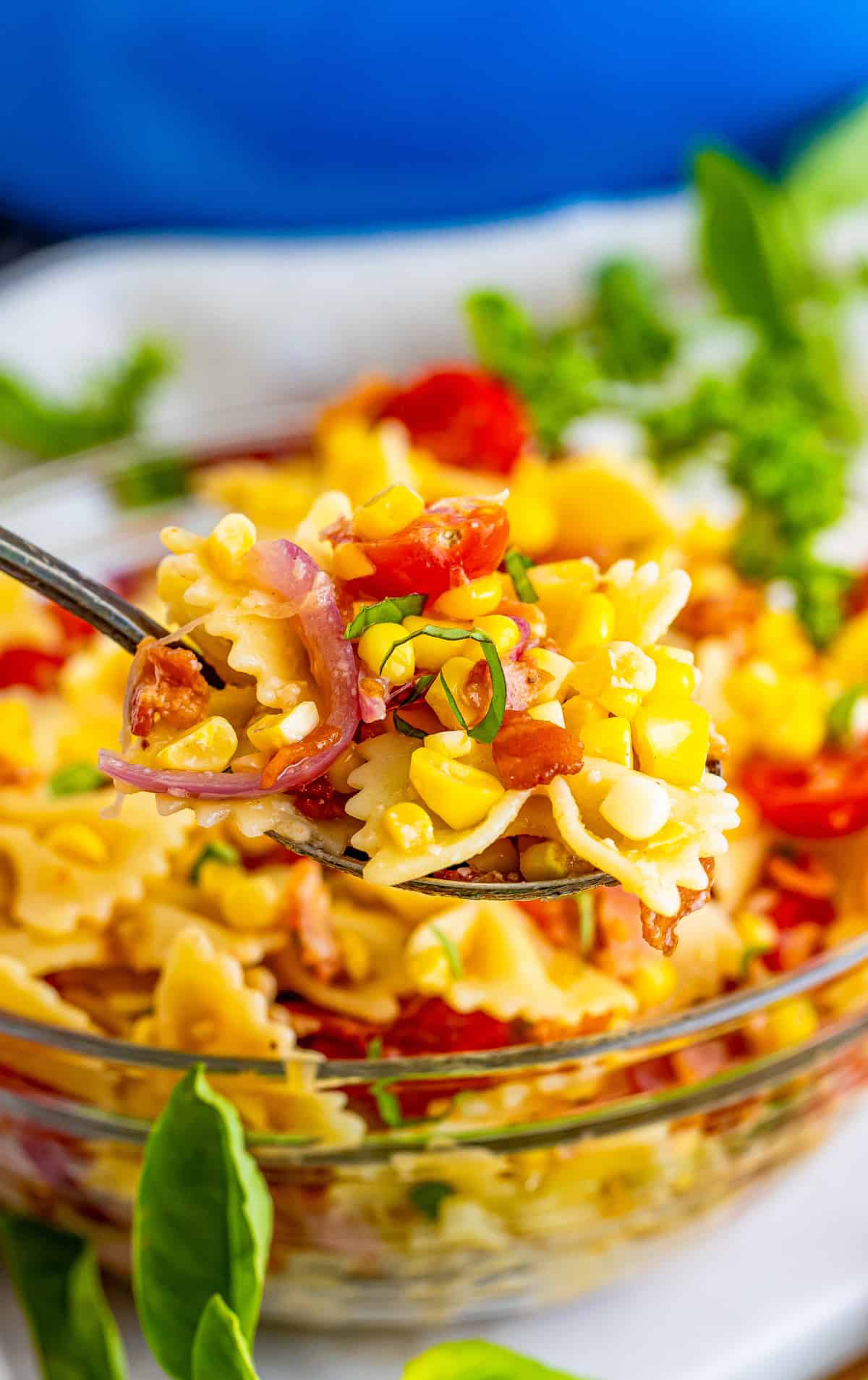 Spoon holding up some of the Bacon and Corn Pasta Salad out of bowl.