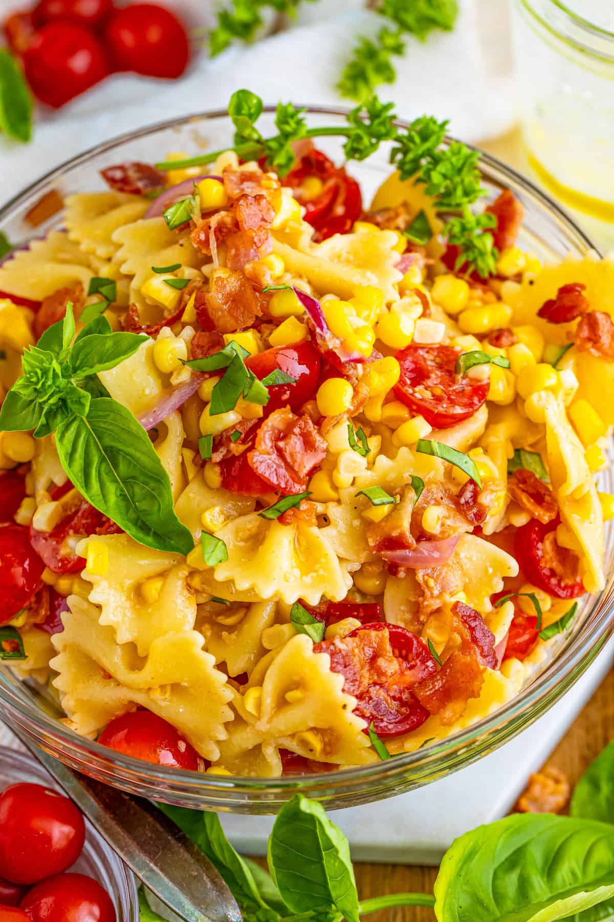 Overhead photo of pasta salad in bowl with everything mixed together and topped with basil.
