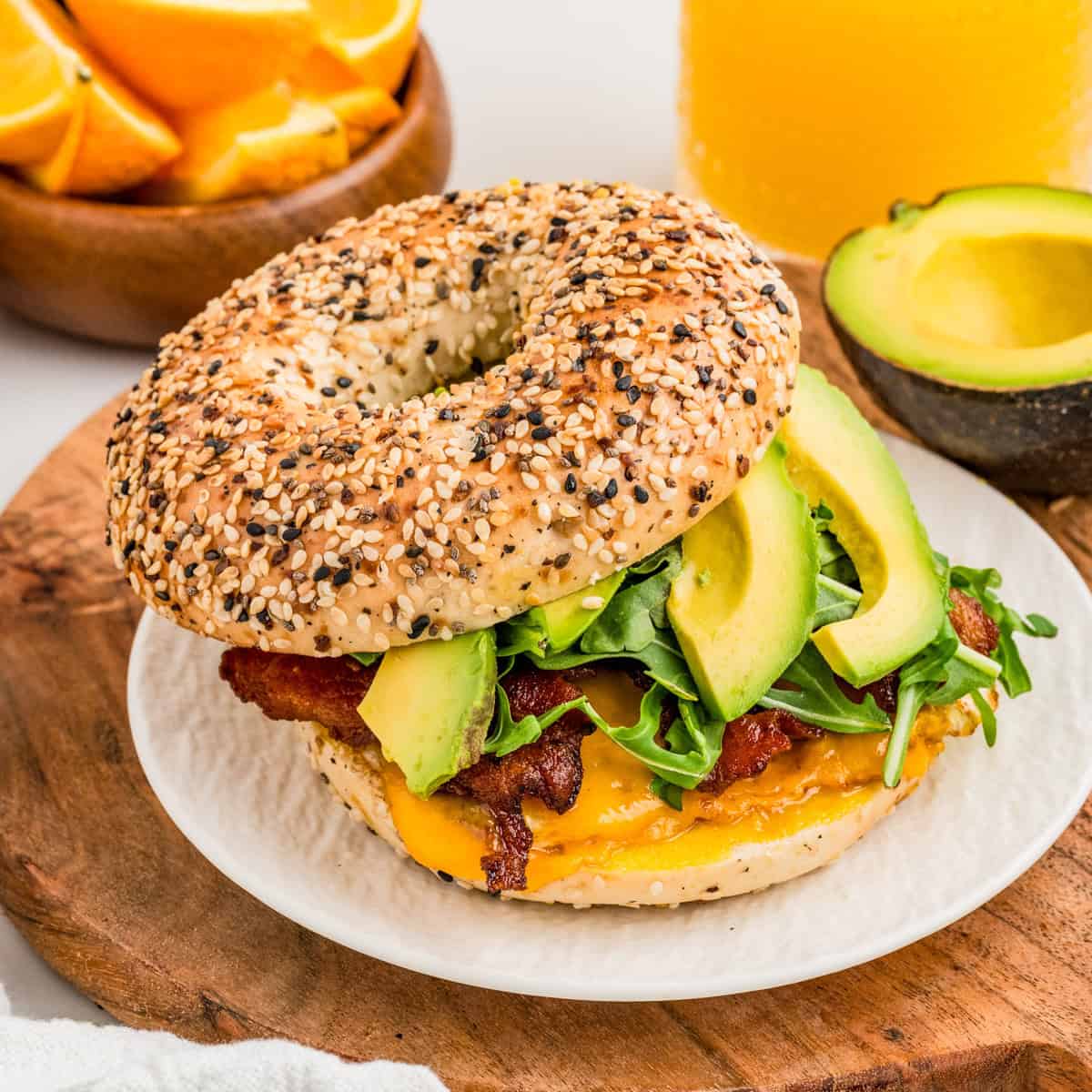 Square image of sandwich on white plate with top bagel off slightly showing the layers of ingredients.