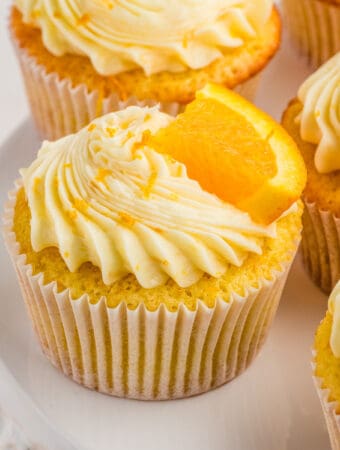 Square image of one cupcake frosted and garnished with an orange slice.