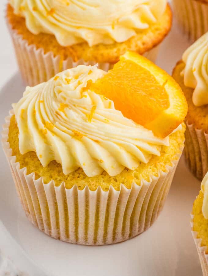 Square image of one cupcake frosted and garnished with an orange slice.
