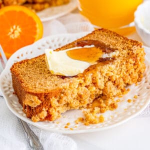 Square image of bread on white plate with butter and syrup.
