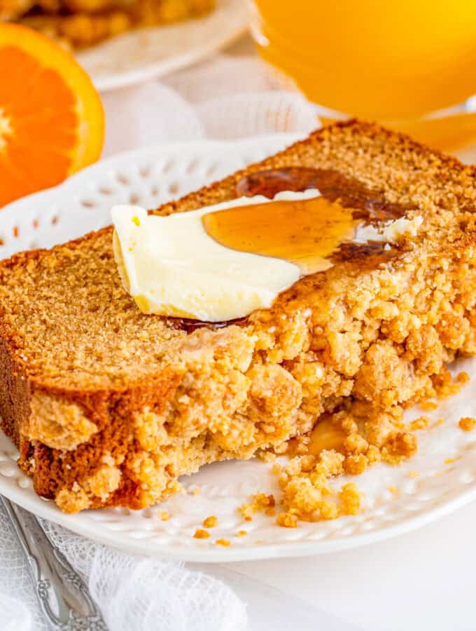 Square image of bread on white plate with butter and syrup.