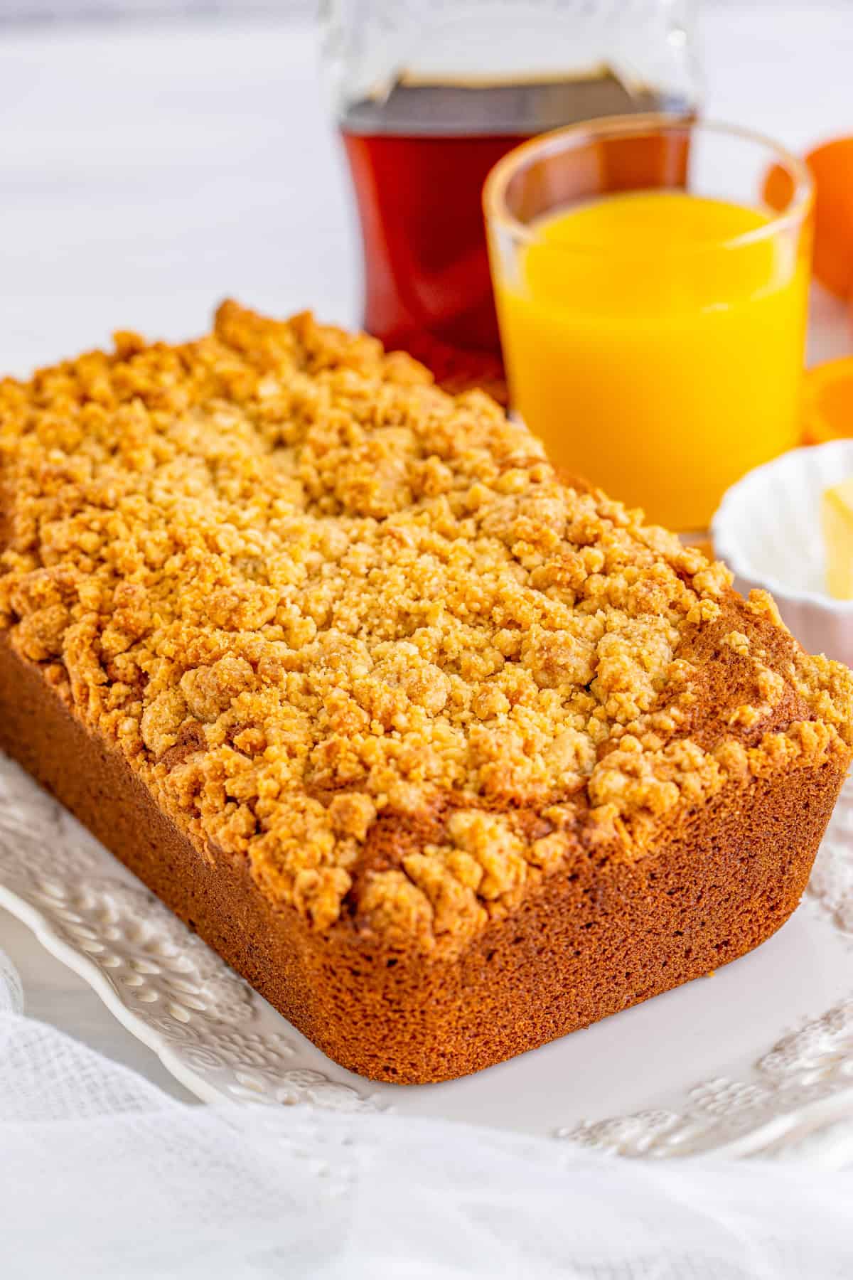 Finished loaf or bread with orange juice and syrup in background.