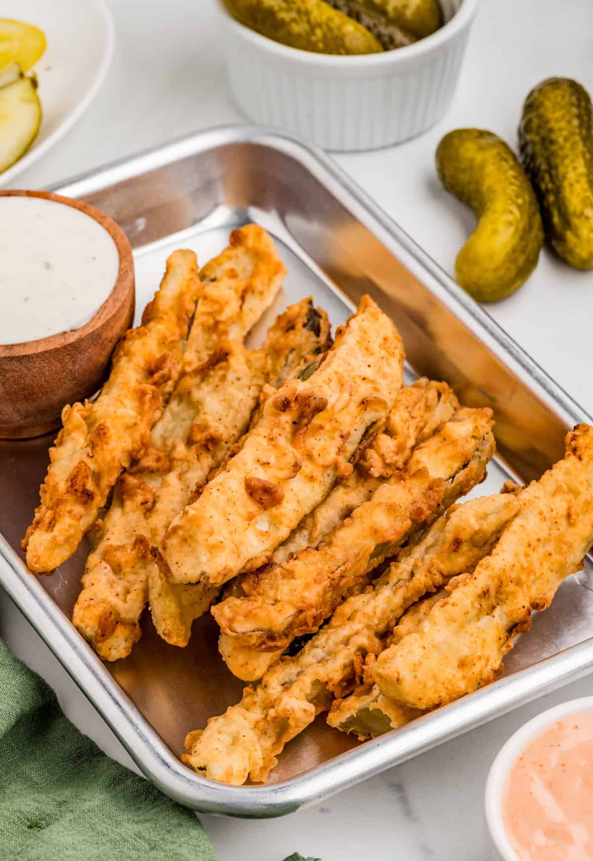 Finished Pickle Fries on metal tray with dipping sauces and pickles in background.