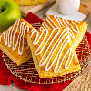 Square image of three strudels on wire rack with icing.