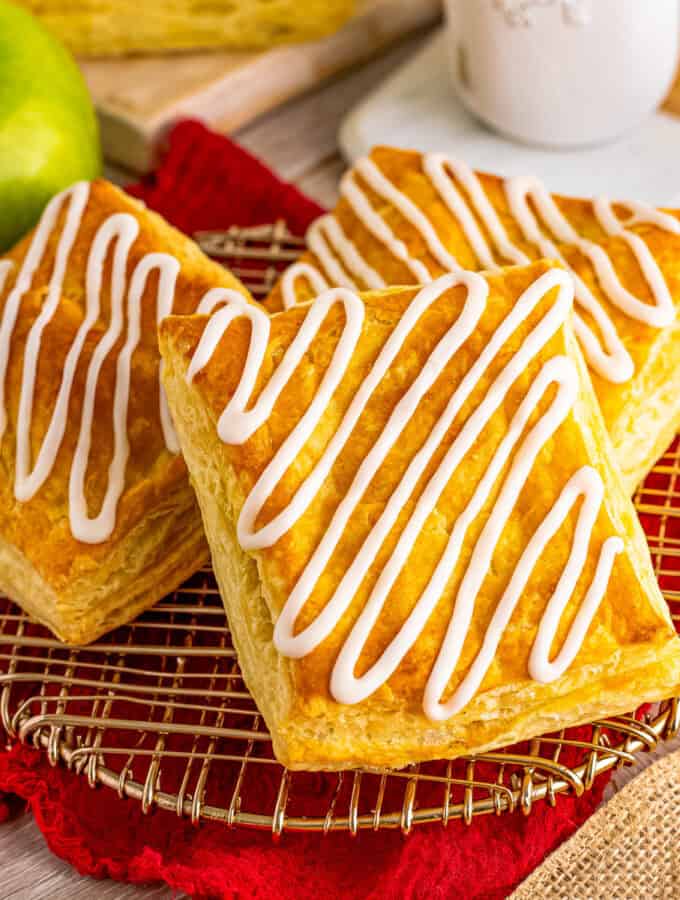 Square image of three strudels on wire rack with icing.