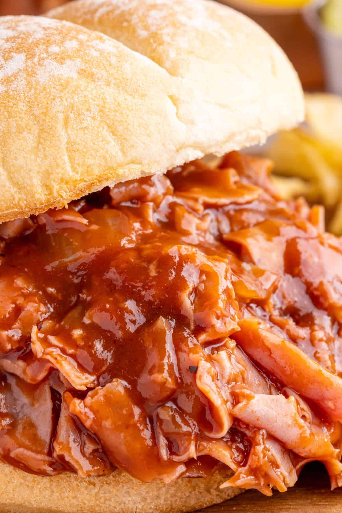 Close up of one BBQ Chipped Ham Sandwich on bun showing the bbq sauce all over the meat.