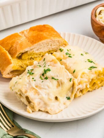 Square image of two rolls on plate with garlic bread.