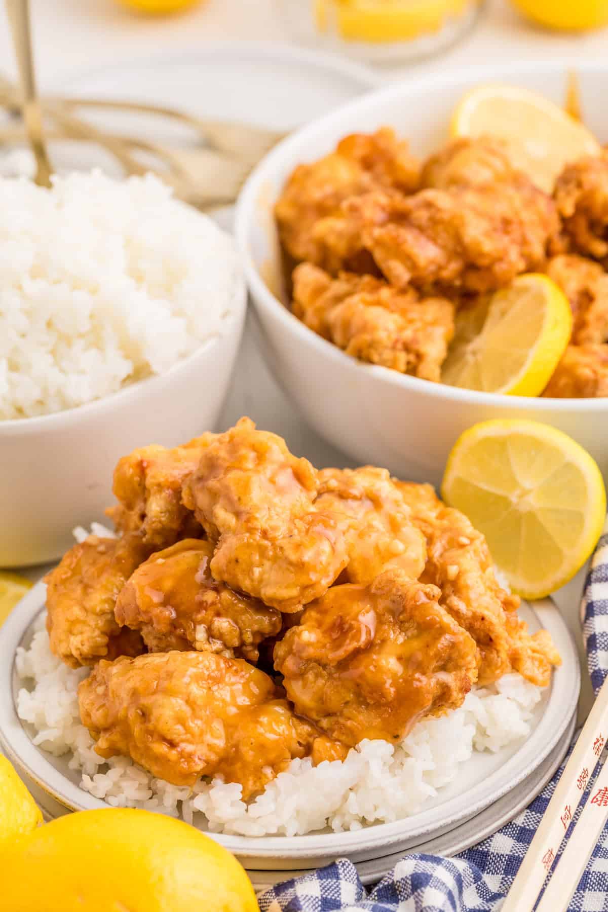 Finished chicken being served over a plate of rice with a bowl of chicken in the background.