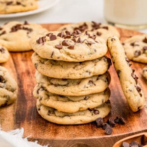 Square image of cookies stacked on wooden platter with one cookie leaning up against the stack.
