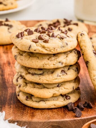 Square image of cookies stacked on wooden platter with one cookie leaning up against the stack.